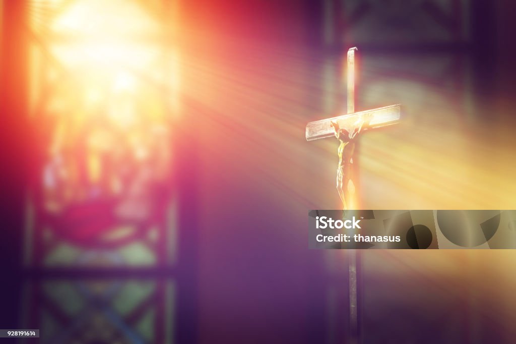 crucifix, jesus on the cross in church with ray of light from stained glass Catholicism Stock Photo
