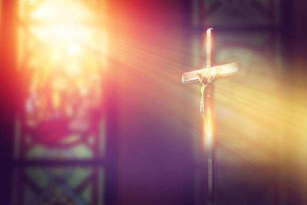 crucifix, jesus on the cross in church with ray of light from stained glass crucifix, jesus on the cross in church with ray of light from stained glass stained glass photos stock pictures, royalty-free photos & images