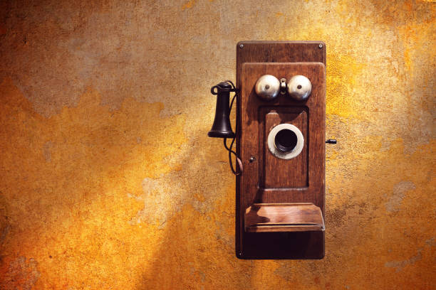 antigos telefones de parede em parede amarelo sujo - telephone receiver - fotografias e filmes do acervo