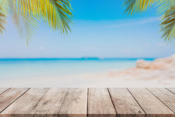 istock Empty wood table top and blurred Palm tree summer beach with blue sea and sky background. - can used for display or montage your products. 928192292