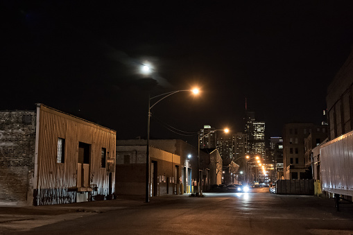 Urban city street with vintage industrial warehouses and the Chicago skyline with the moon at night