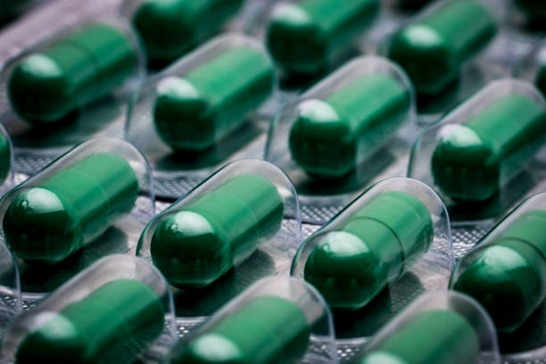 istock Andrographis paniculata extract for treatment common cold and sore throat. Standardized herbal medicine capsule pills in pack. Full frame of green capsule pills. Alternative medicine concept. 928201054