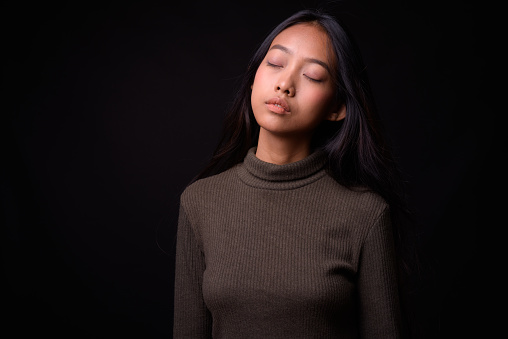 Studio Shot Of Beautiful Asian Woman Against Black Background