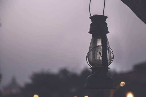 Closeup of old oil lantern hangs from a wooden beam.