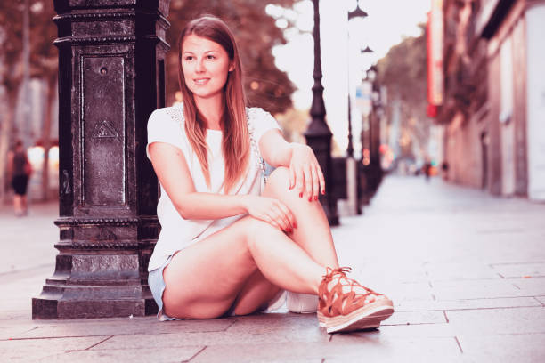 istock Young woman sitting near lamp post 928230866