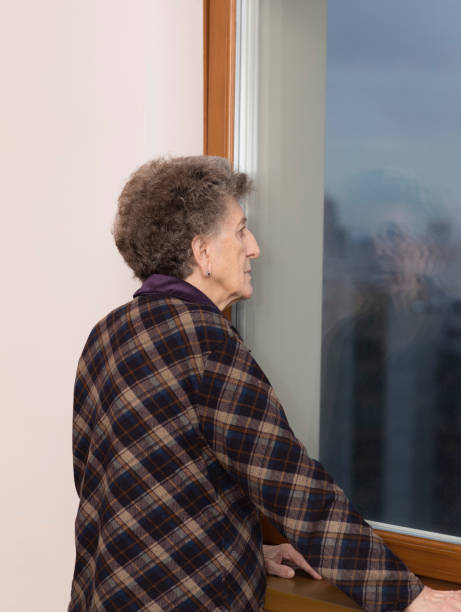 istock Old woman stays close to the window 928235896