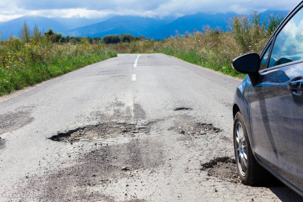 carro e asfalto rachado com furos - pot hole - fotografias e filmes do acervo