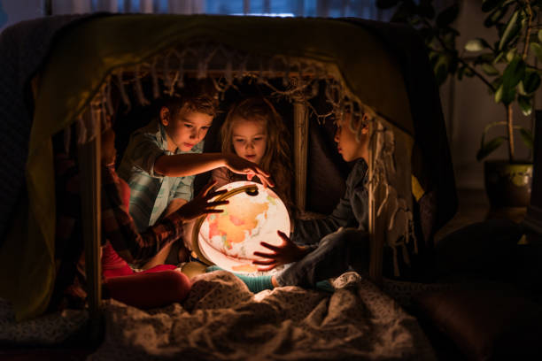 Group of small kids exploring globe in a tent at home.