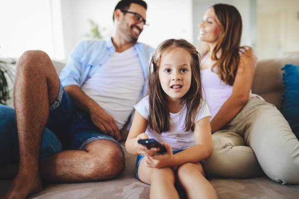 istock Young girl watching tv with her parents 928254682