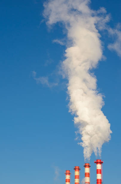 istock Plant pipes with smoke against blue sky 928255998