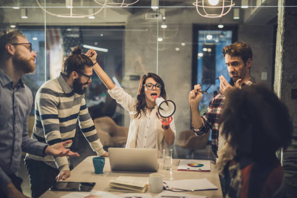 istock Young woman shouting through megaphone while having a meeting with her colleagues in the office. 928272298