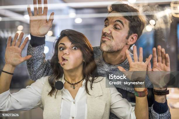 Foto de Jovens Empreendedores Brincalhão Fazendo Caretas Enquanto Brincava Com Parede De Vidro e mais fotos de stock de Janela