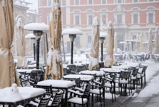 Outside bar tables covered with snow. Brescia, Italy.