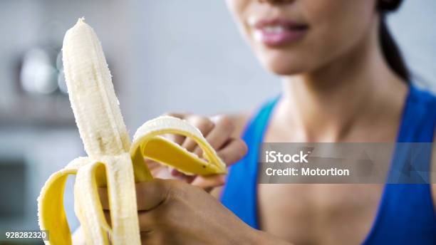 Sports Woman Peeling Sweet Banana For Snack Hungry After Active Workout In Gym Stock Photo - Download Image Now