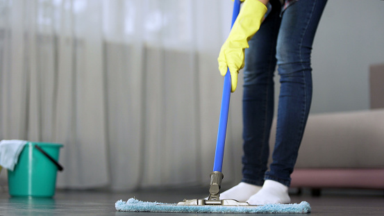 Housewife carefully washing floor in her apartment with mop, spring-cleaning, stock footage