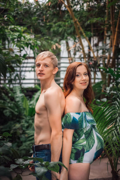 joven pareja de pronto a ser padres en el bosque tropical - shirtless jeans women blond hair fotografías e imágenes de stock