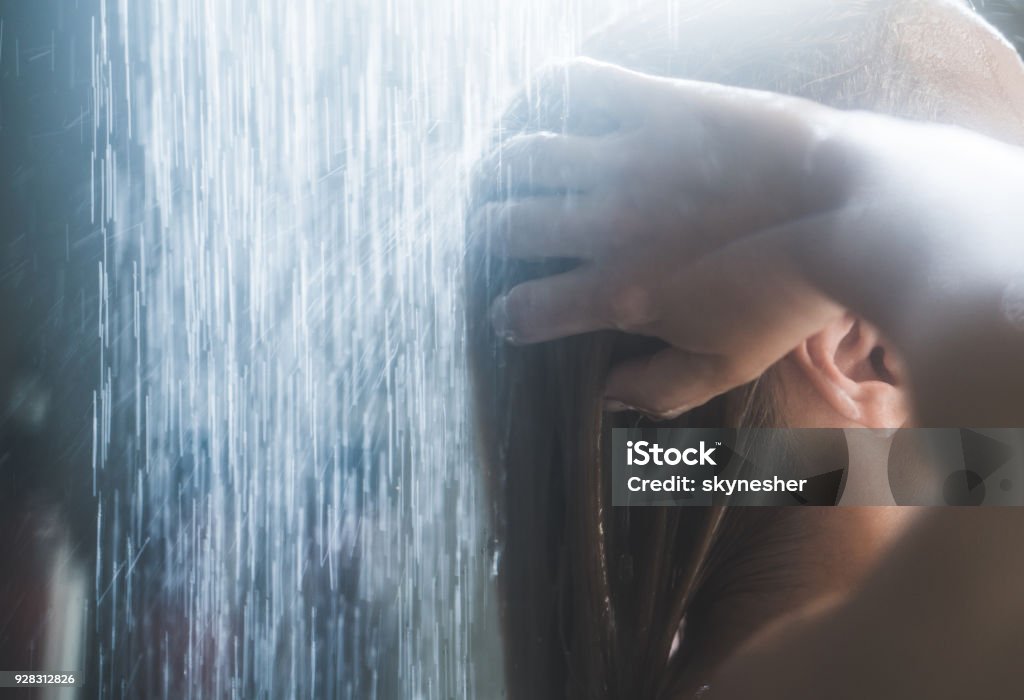 Close up of unrecognizable woman washing her hair under the shower. Close up of a woman washing her hair while showering in the morning. Shower Stock Photo
