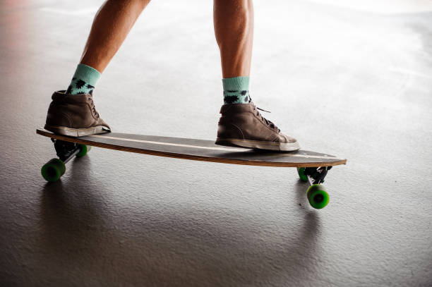 istock Mans legs in sneakers standing on a longboard 928314962