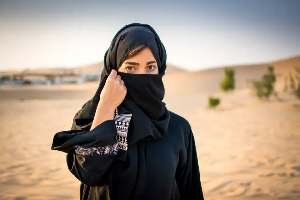 Photo of Portrait of beautiful Muslim woman wearing traditional Arabian clothing in the desert.