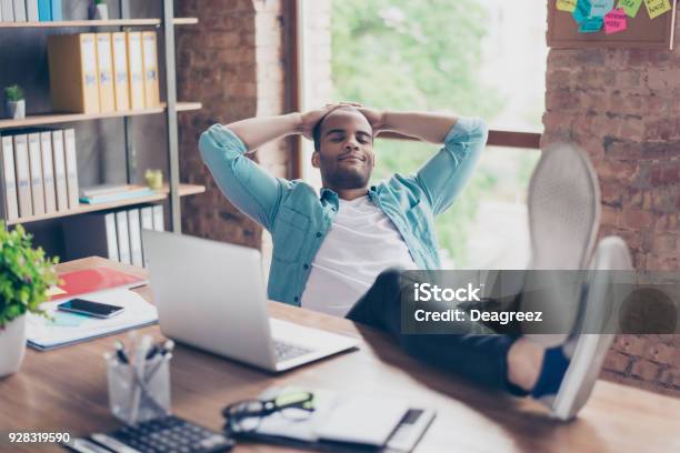 Young Cheerful Afro Freelancer Is Resting At A Workplace With Feet On Top Of The Desk With Closed Eyes Smiling Dreaming Stock Photo - Download Image Now