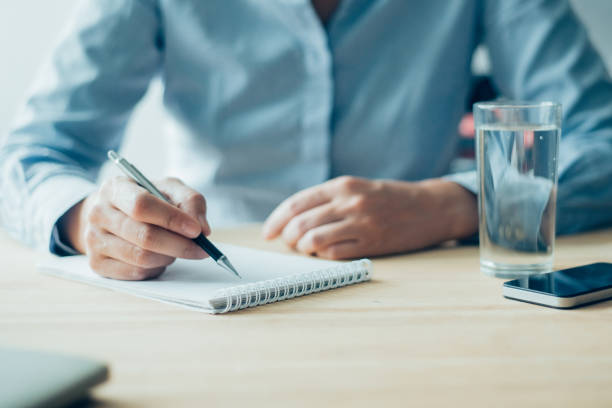 istock Closeup of Woman Writing in Notebook in Office 928320186