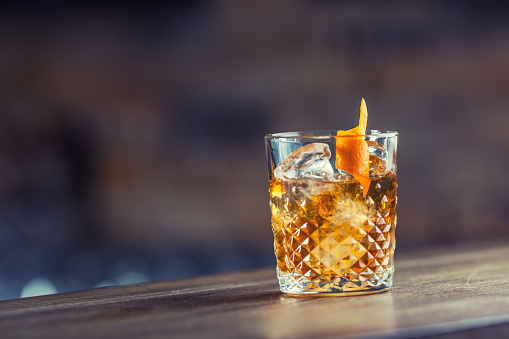 Old fashioned classic cocktail drink in crystal glass on bar counter.