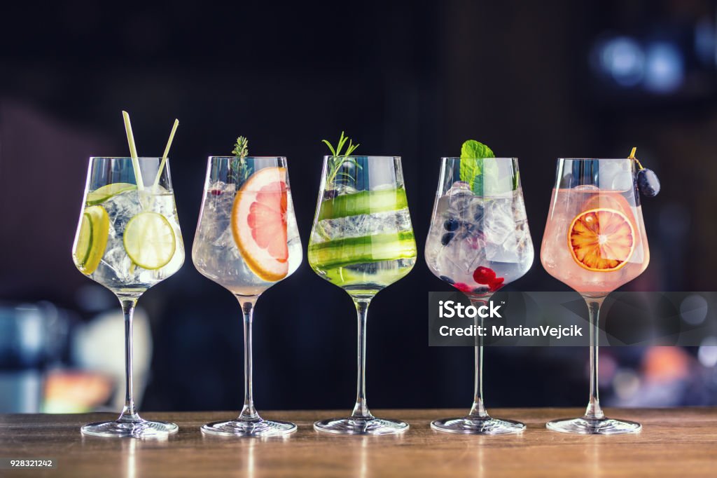 Five colorful gin tonic cocktails in wine glasses on bar counter in pup or restaurant Five colorful gin tonic cocktails in wine glasses on bar counter in pup or restaurant. Cocktail Stock Photo