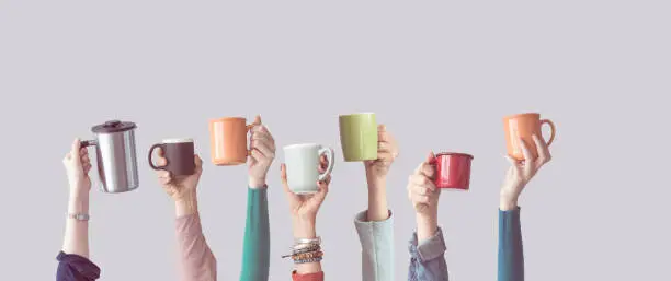 Many different arms raised up holding coffee cup