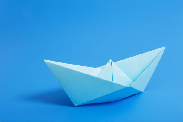 istock paper boat on blue paper background 928334746