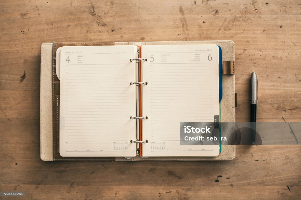 Open empty spiral hard cover notebook next to pen wooden background Personal Organizer Stock Photo