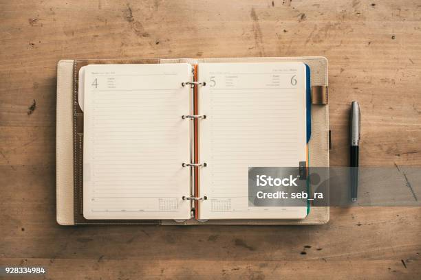 Open Empty Spiral Hard Cover Notebook Next To Pen Wooden Background Stock Photo - Download Image Now