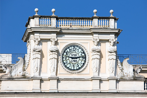 Antique clock on facade of an old classic building in Rome, Italy