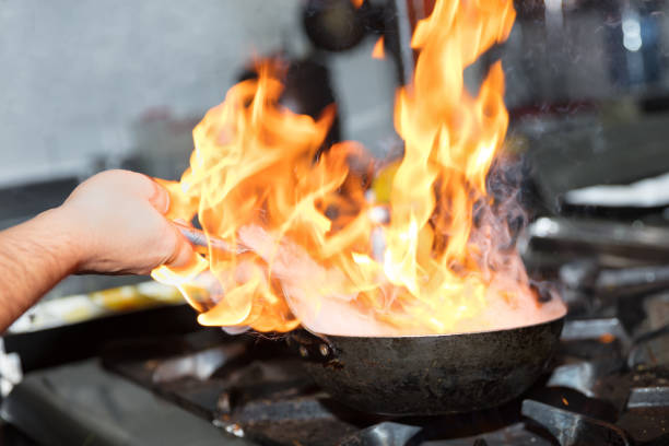 istock Chef cooking with flame in a frying pan on a kitchen stove. 928336870
