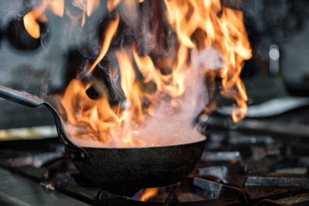 istock Chef cooking with flame in a frying pan on a kitchen stove. 928337722