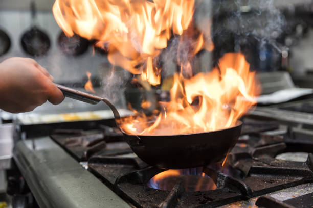 istock Chef cooking with flame in a frying pan on a kitchen stove. 928338014