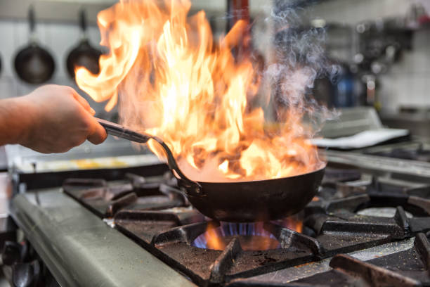 istock Chef cooking with flame in a frying pan on a kitchen stove. 928342462