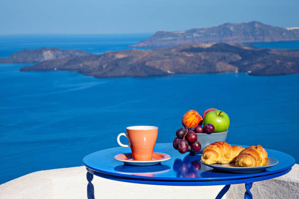 colazione con croissant e frutta fresca al mattino presto servita sul balcone con vista vulcanica sul mare. - beach table peach fruit foto e immagini stock