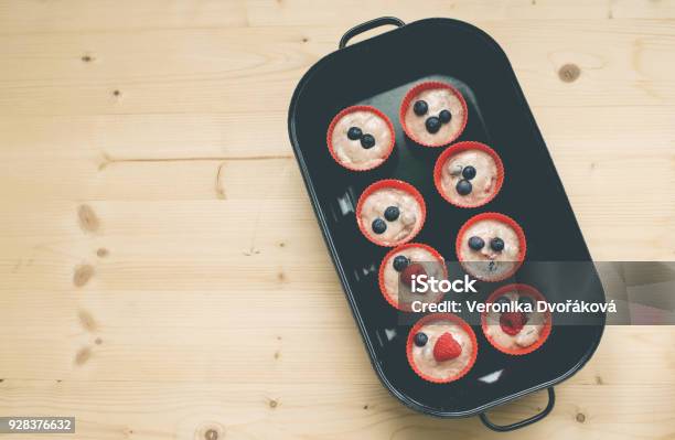 The Muffins With Raspberries And Blueberries In Red Cups Prepared For Baken In Bakenform Stock Photo - Download Image Now