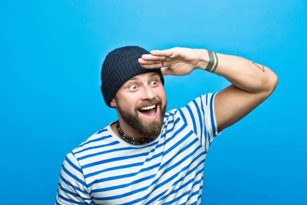 Photo of Excited bearded sailor looking away with raised hand