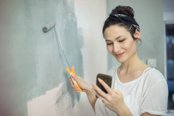 istock Young Woman Painting Walls 928391504