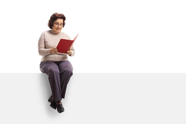 istock Elderly woman sitting on a panel and reading a book 928395336