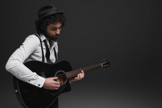 istock handsome bearded musician playing acoustic guitar on black 928399738