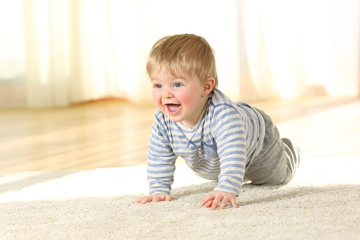 Portrait of a cute baby crawling and laughing on the floor at home