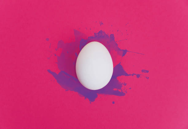 istock One white egg on bright pink background with violet watercolor splatters 928400196
