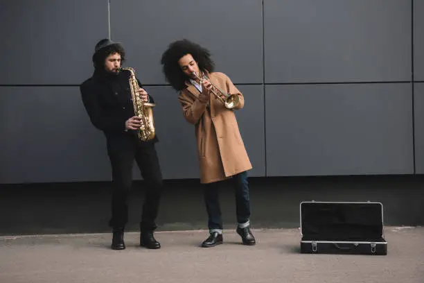 duet of street jazzmen playing trumpet and saxophone outdoors