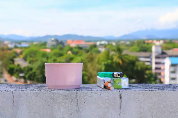 coffee cup pink and a cigarette pack lighter on the floor. with city blue sky background concept Non-smoking day universal