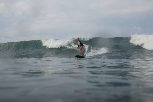 istock girl riding wave on surf board in ocean 928404558