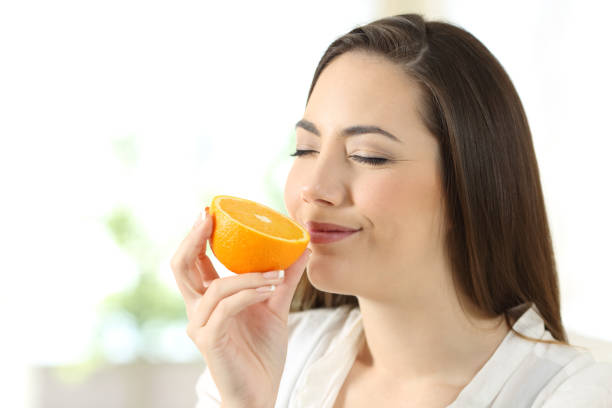 istock Pretty woman smelling half orange at home 928407178