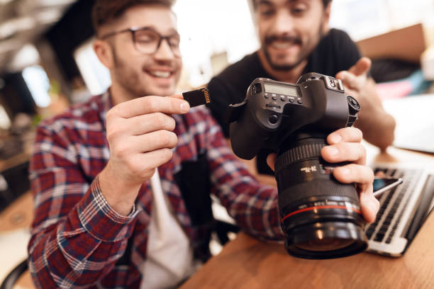 istock Two freelancer men taking out memory card at laptop at desk. 928407456