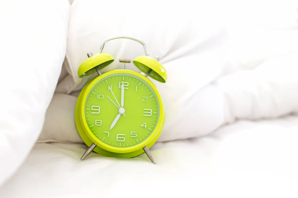 istock Alarm clock on bed in morning with sun light 928407712